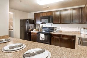Magna apartment for rent - a kitchen with wooden cabinets and black appliances