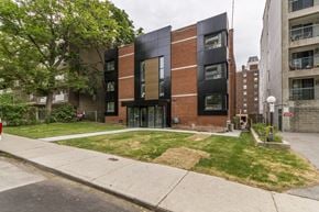 Hamilton apartment for rent - A modern building with a black and brown facade is situated on a street corner.