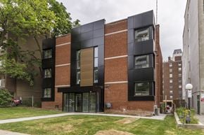 Hamilton apartment for rent - A modern brick building with black windows and a green lawn in front.