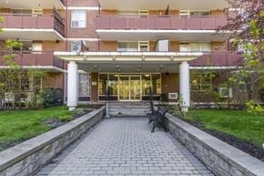 Mississauga apartment for rent - A brick building with a covered walkway leading to the entrance.