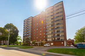 Hamilton apartment for rent - A tall apartment building with a sun shining in the background.