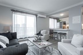 Hamilton apartment for rent - A modern living room with a grey couch, a black chair, and a glass coffee table.