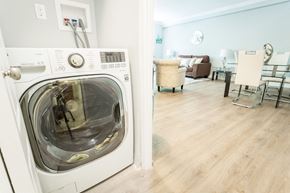 Hamilton apartment for rent - A white front loading washing machine in a room with a wooden floor.