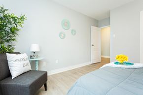Hamilton apartment for rent - A bedroom with a grey bedspread and a grey couch with a pillow that says "BIG".