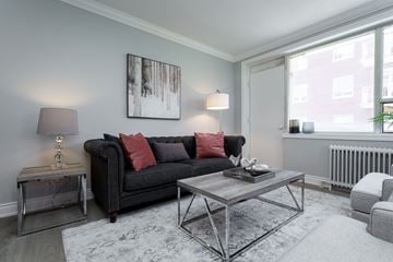 Hamilton apartment for rent - A living room with a black couch, a grey coffee table, and a large painting on the wall.