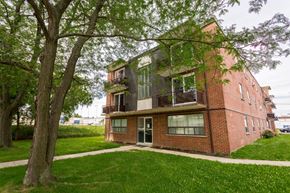 Hamilton apartment for rent - A red brick house with a balcony and a tree in front.
