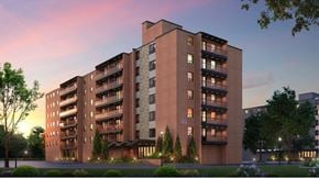 North York apartment for rent - A large apartment building with balconies and lights on the ground floor.