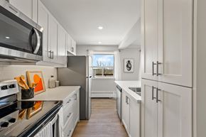 North York apartment for rent - A modern kitchen with white cabinets and stainless steel appliances.
