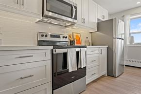 Stoney Creek apartment for rent - A modern kitchen with white cabinets and stainless steel appliances.