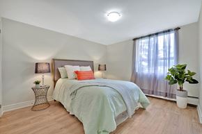 Hamilton apartment for rent - A bedroom with a bed, a nightstand, and a potted plant.