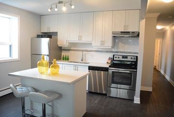 Hamilton apartment for rent - A kitchen with white cabinets and a white island with two yellow bottles on it.
