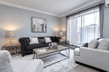 Hamilton apartment for rent - A living room with a black couch, a grey couch, a coffee table, and a painting on the wall.
