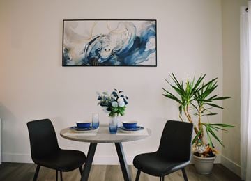 Berlin apartment for rent - A dining room with a table set for two and a large abstract painting on the wall.