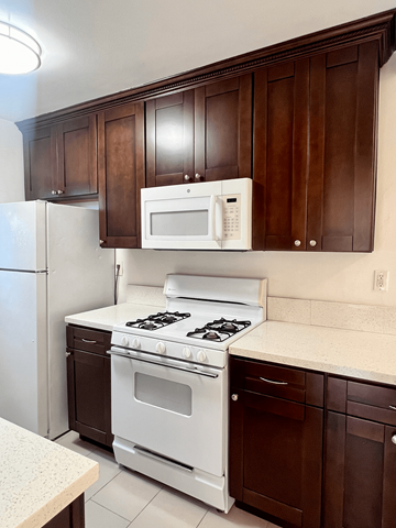 West Hollywood apartment for rent - a kitchen with white appliances and dark wood cabinets