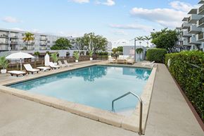 Lauderhill apartment for rent - A swimming pool surrounded by a concrete border and lounge chairs.