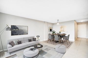 Lauderhill apartment for rent - A modern living room with a grey sofa, a grey dining table and chairs, and a grey rug.