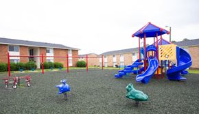Fayetteville apartment for rent - A playground with a blue slide and a red and blue playhouse.
