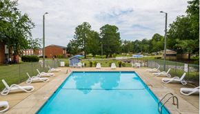 Fayetteville apartment for rent - A large swimming pool surrounded by white lounge chairs.
