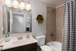 Louisville apartment for rent - A bathroom with a white toilet, a sink, a mirror, and a shower.