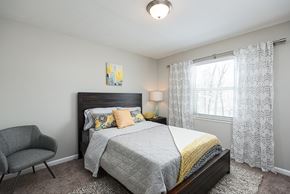 Louisville apartment for rent - A bedroom with a bed, chair, and window.