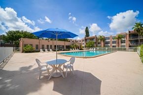 North Miami apartment for rent - A pool area with a table and chairs and a blue umbrella.