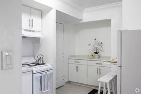 Miami apartment for rent - A small white kitchen with a stove and a counter.