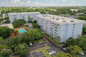 Plantation apartment for rent - A large white apartment building with a pool in the courtyard.