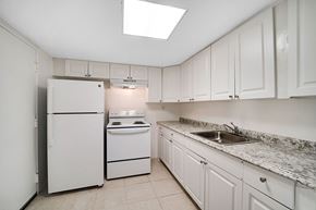 Plantation apartment for rent - A white kitchen with a refrigerator, stove, and sink.