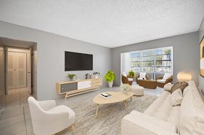 Plantation apartment for rent - A living room with a white sofa, a wooden coffee table, and a flat-screen TV mounted on the wall.