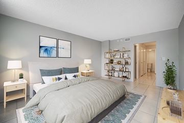 Plantation apartment for rent - A bedroom with a large bed and a small table with a lamp on it.