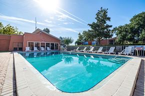 Tampa apartment for rent - A large outdoor swimming pool with sun loungers and a building in the background.