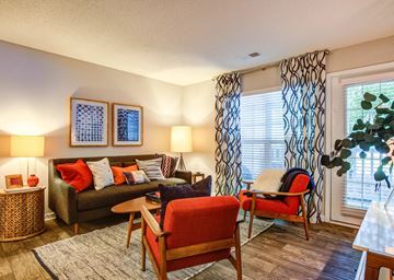 North Charleston apartment for rent - A living room with a red chair and a brown couch.