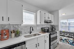 Raleigh apartment for rent - A modern kitchen with white cabinets and a black stove top oven.