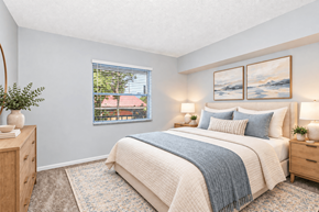 Largo apartment for rent - A bedroom with a large bed and a window showing a view of a red roof.