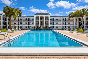 Largo apartment for rent - A large swimming pool in front of a building with palm trees.