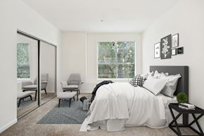Raleigh apartment for rent - A bedroom with a large bed and a window with a view of trees.