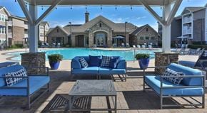 Greenville apartment for rent - a swimming pool with blue lounge chairs and a table