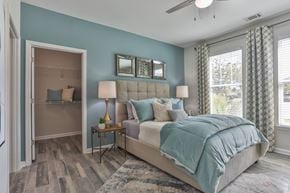 Greenville apartment for rent - A bedroom with a large bed and a dresser with a mirror above it.