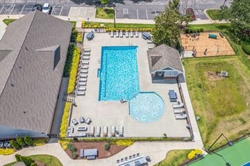 Raleigh apartment for rent - An aerial view of a swimming pool surrounded by a grassy area and a parking lot.
