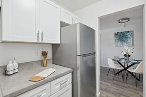 Largo apartment for rent - a kitchen with white cabinets and stainless steel appliances and a dining room with a table