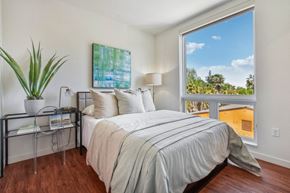 Sacramento apartment for rent - A bedroom with a large bed and a view of the outdoors through a window.
