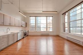 Denver apartment for rent - A large empty room with wooden floors and a window overlooking a cityscape.