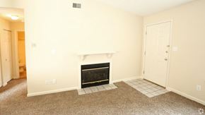 Louisville triplex for rent - A living room with a fireplace and a carpet.