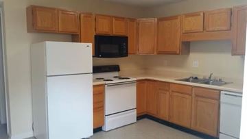 Louisville triplex for rent - A kitchen with wooden cabinets and white appliances.