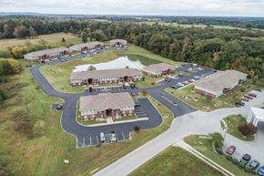 Bardstown apartment for rent - A large building complex with a parking lot in front.