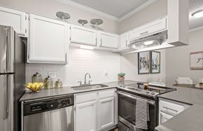 Dallas apartment for rent - A modern kitchen with white cabinets and stainless steel appliances.