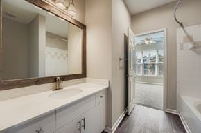 Alpharetta apartment for rent - A bathroom with a sink, mirror, and bathtub.