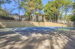 Alpharetta apartment for rent - A tennis court surrounded by trees and apartment buildings.