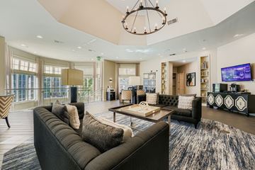 Alpharetta apartment for rent - A modern living room with a large grey sofa and a chandelier.