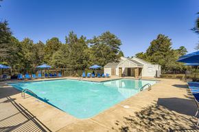 Roswell apartment for rent - A large swimming pool surrounded by trees and a building in the background.